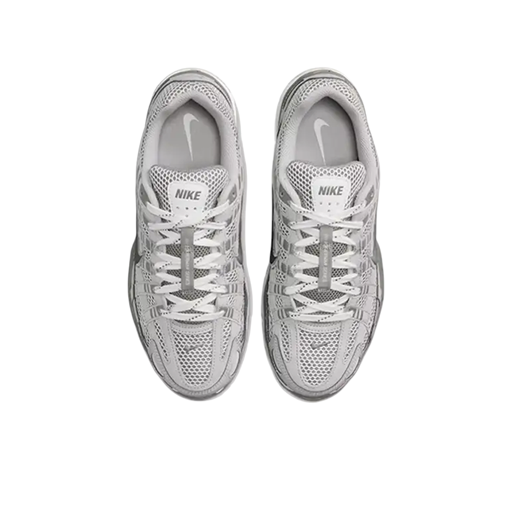 JeevzPlug Nike P-6000 Light Iron Ore sneakers featuring mesh and leather overlays in grey and metallic silver tones.