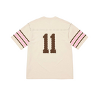 JeevzPlug Supreme cream short sleeve football jersey with studded shoulder detail and brown number 11 on the back.