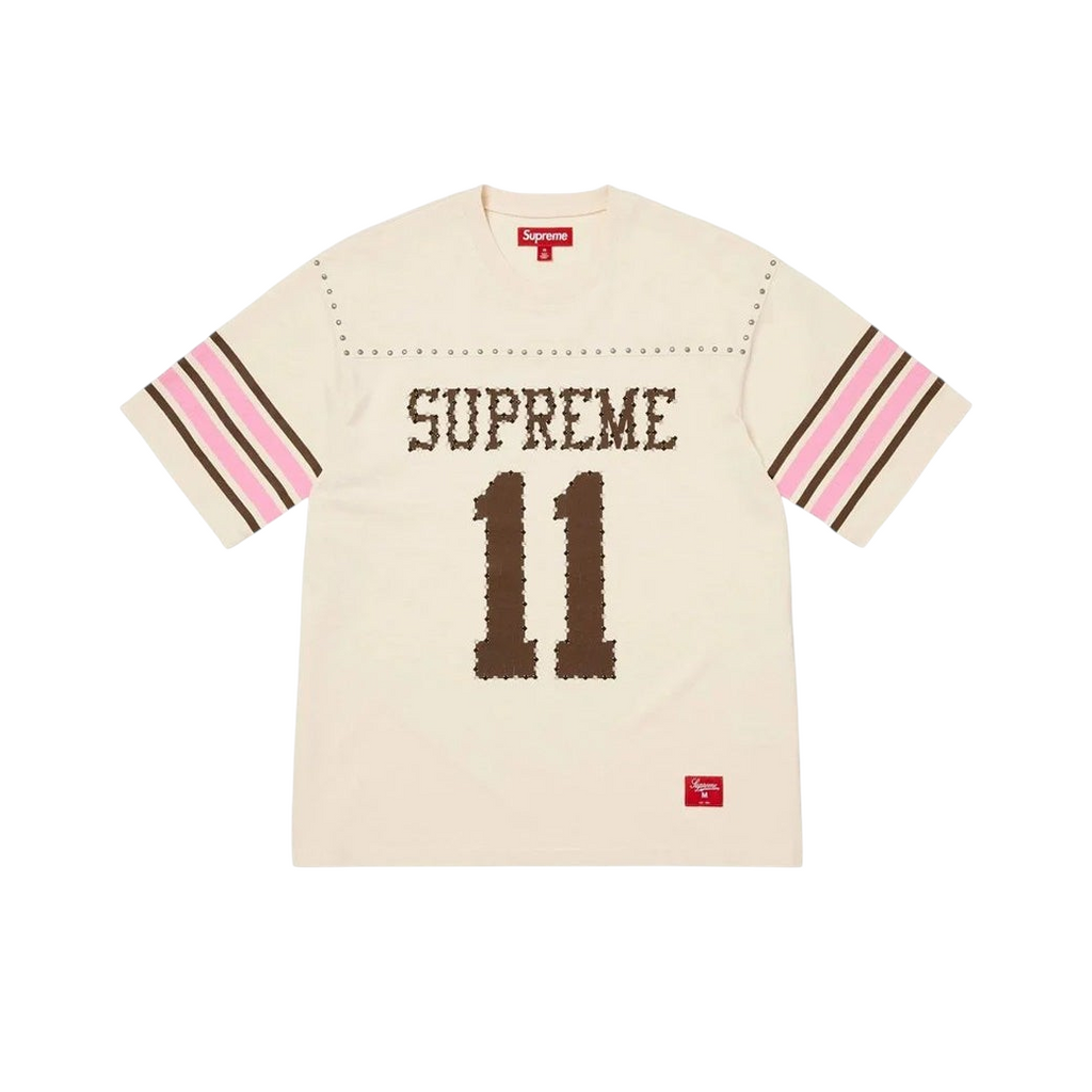 JeevzPlug Supreme cream short sleeve football jersey with studded detailing, brown graphic text, and striped sleeves.
