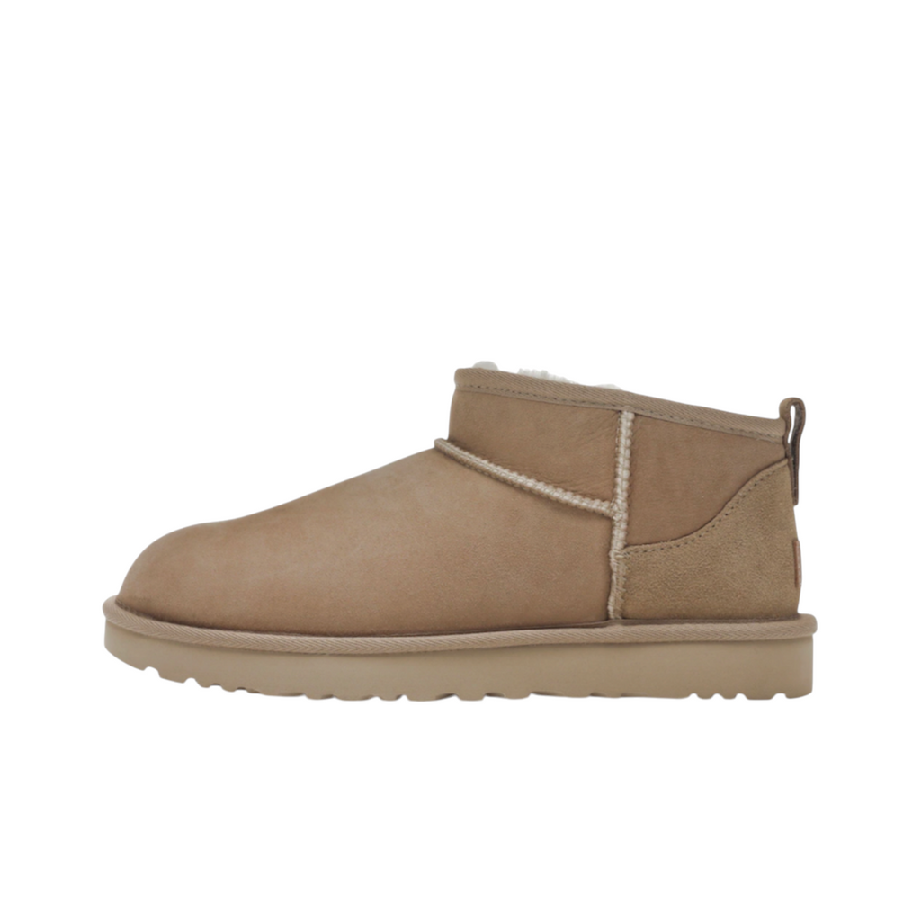 JeevzPlug UGG Ultra Mini boot in sand suede with a low-cut ankle and plush sheepskin lining, side profile view.
